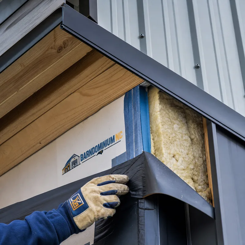 Barndominium wall and roof assembly showing metal panels, flashing, weather barrier, and insulation near an eave transition